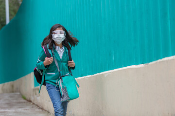 Mexican little girl going back to school wearing plastic face mask after coronavirus pandemic