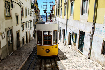 Naklejka na ściany i meble Yellow vintage tram on the street in Lisbon, Portugal. Famous travel destination. Lisboa tram in narrow street.