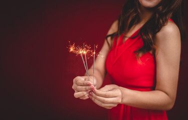 Woman in red dress celebrating the new year holding fireworks.