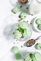 Homemade mint chocolate chip macarons with a mint buttercream filling in a clear sundae glass