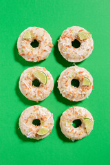 Homemade key lime donuts with a toasted coconut topping on a bright green background