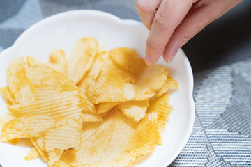 美味しそうなポテトチップスを食べようとしている所の写真。太りそうなお菓子のイメージ。