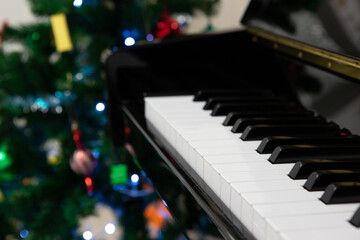 A piano with christmas  tree background, shallow focus on key D.