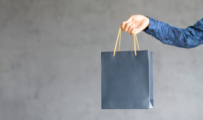 man hand holding shopping bag and copy space gray background, design banner onling shopping concept