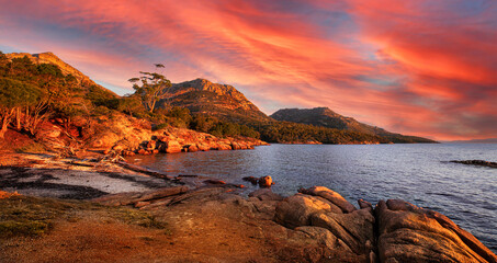 Landscape view of natural sea coast with mountain range in evening sunset  in orange-red and blue...