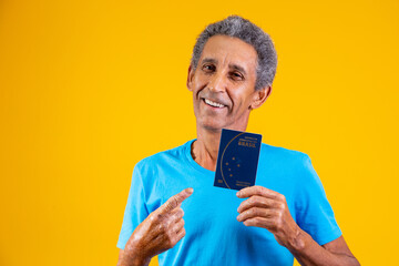 Afro elderly man holding brazilian passport in hands.