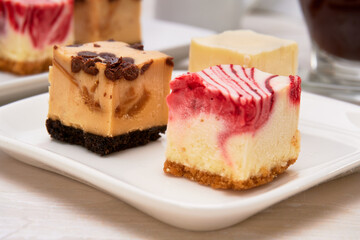 three new york cheese, chocolate and caramel, strawberry and lemon mini mini pie on a white plate on a white marble surface and white background. copy space for advertising. fancy concept. macro