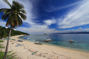 Pristine beach with clear blue water and traditional boats in the Philippines