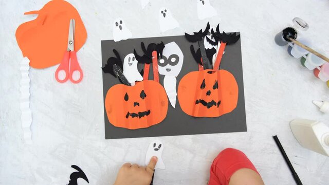 Child making pumpkins for the holiday of halloween. Funny crafts from paper. Halloween decor. Handicraft. The concept for Halloween. DIY. Children's art project, a craft for children.