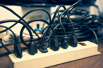Old and damaged electric adapter power plug has many appliances are plugged outlet socket concept...