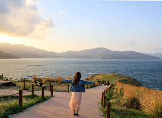 Fototapeta na wymiar A woman enjoying the wind while looking at the beautiful mountains and sea