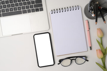 Top view mock up mobile phone, laptop and notebook on white table..