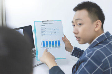 Fototapeta na wymiar Business partners concept a young businessman pointing at profit summary of the recent month showing in document forms