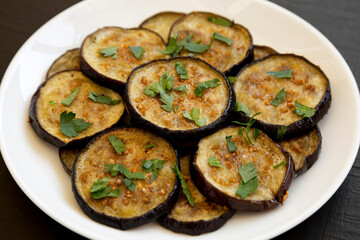 Homemade Organic Roasted Eggplant on a white plate on a black background, side view. Close-up.