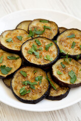 Homemade Organic Roasted Eggplant on a white plate on a white wooden background, side view. Close-up.