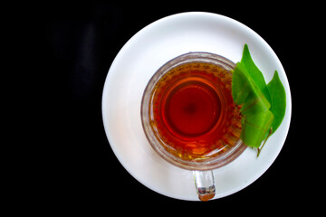 Black tea isolated on black background with tender tea leaves. Green tea in a glass cup.