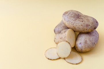 Fototapeta premium Potato tubers and half a potato on a colored background. Potatoes on a colored background of kopi space 