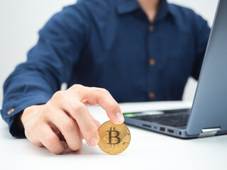 Close up hand holding golden bitcoin on the table with laptop crop shot