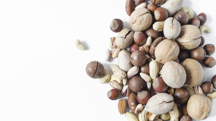 a scattering of different nuts on a white background assorted nuts hazelnuts almonds pecans peanuts macadamia walnuts top view kopi space	