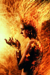 Young woman with burning hair holds flames in her hands. The woman's skin is charred, cracked and...