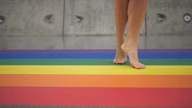 Slow motion of feet walking barefoot on LGBT rainbow colored crosswalk, Concept of pride month and self-affirmation.