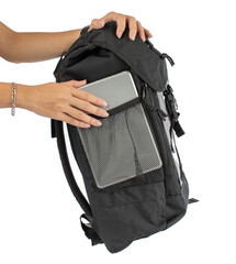 Isolated closeup studio shot of female hands putting silver touchscreen tablet inside elastic net side compartment pocket of canvas fabric urban trendy black backpack in front of white background