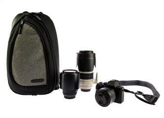 Isolated close up studio shot of big black dslr camera with neck strap telephoto and wide angle lens and trendy urban professional photographer shockproof waterproof backpack on white background