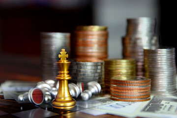 golden chess on board with coins stacking on bank note , business concept