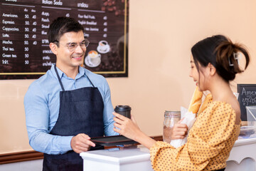 Business Owner. A cheerful successful small business owner standing to welcome. Selling to customers at the counter in coffee shops and convenience stores.