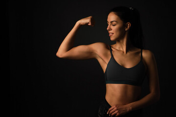 fitness young woman with a healthy toned body, showing muscles isolated on black