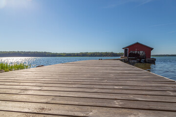 Wooden jetty, boathouse and ocean in Åland Islands, Finland, on a sunny day in the summer. Low angle view, focus on the front.
