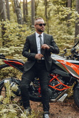 Fototapeta na wymiar Cool man and black red colored motorbike in forest