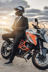 Fototapeta na wymiar Cool businessman with motorcycle helmet posing against seascape