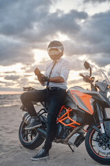 Fototapeta na wymiar Confident biker in white shirt and helmet with motorbike
