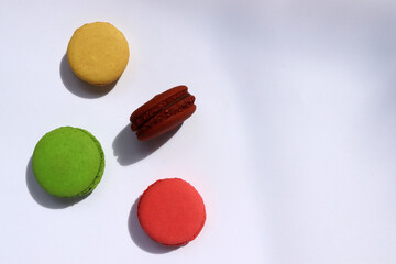 Colorful macaroons on white background. Hard light, shadow. Top view, copy space.