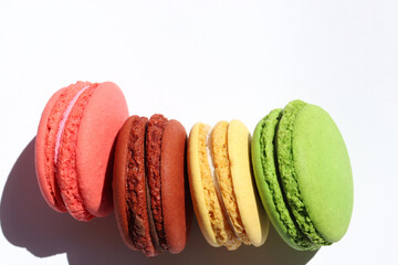 Colorful macaroons on white background. Hard light, shadow. Top view, copy space.