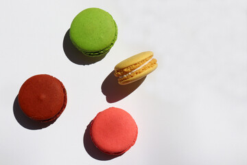 Colorful macaroons on white background. Hard light, shadow. Top view, copy space.