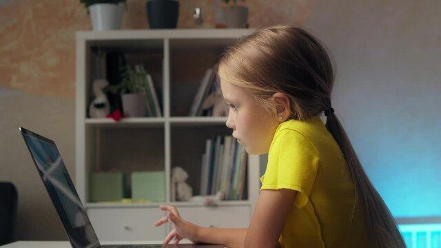 Blonde girl 6 years old uses a laptop