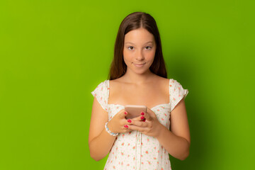 A girl using smartphone in summer dress isolated over green background.