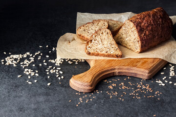 Bread with sunflower and flax seeds on a wooden cutting board on a black background