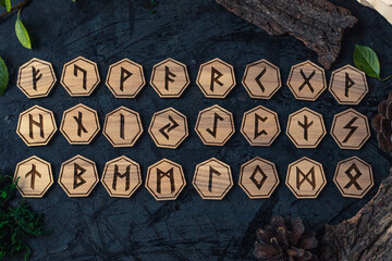 Wooden runes are lying on the table among various objects. Astrology and esotericism. Senior Futhark