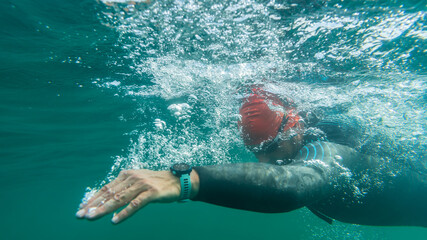 Athlete in a wetsuit swims in open water - obrazy, fototapety, plakaty