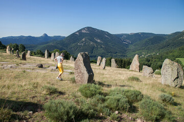 Touriste promenant dans un champ de menhirs dans un paysage des monts d'Ardèche