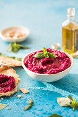 red beetroot hummus on blue background, lemon, sesame, olive oil, pita. Middle eastern, jewish, arabic cuisine.