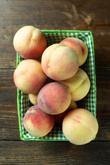 Ripe peaches in a basket on a wooden table with scattered leaves. Fresh homemade fruits.
