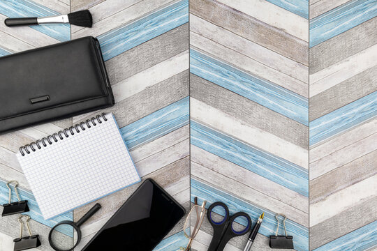 Artistic office or business background with copyspace on a zig-zag wood pattern with mobile phone, purse and stationery supplies as a corner border and copyspace