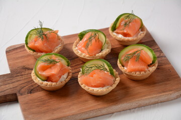 Tartlets with salmon, cheese, cucumber and dill. Tasty snacks with salted salmon and cottage cheese filling