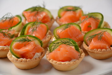 Tartlets with salmon, cheese, cucumber and dill. Tasty snacks with salted salmon and cottage cheese filling
