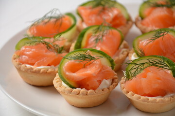 Tartlets with salmon, cheese, cucumber and dill. Tasty snacks with salted salmon and cottage cheese filling