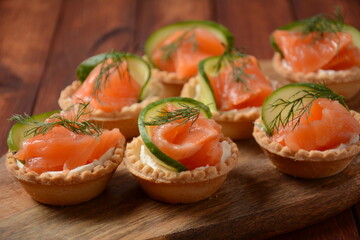 Tartlets with salmon, cheese, cucumber and dill. Tasty snacks with salted salmon and cottage cheese filling